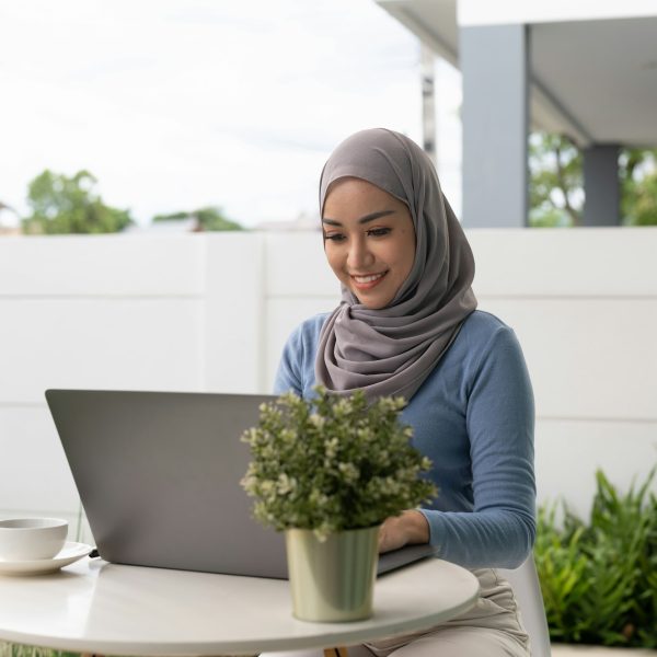 Portrait of Muslim asian woman in hijab using laptop at home.